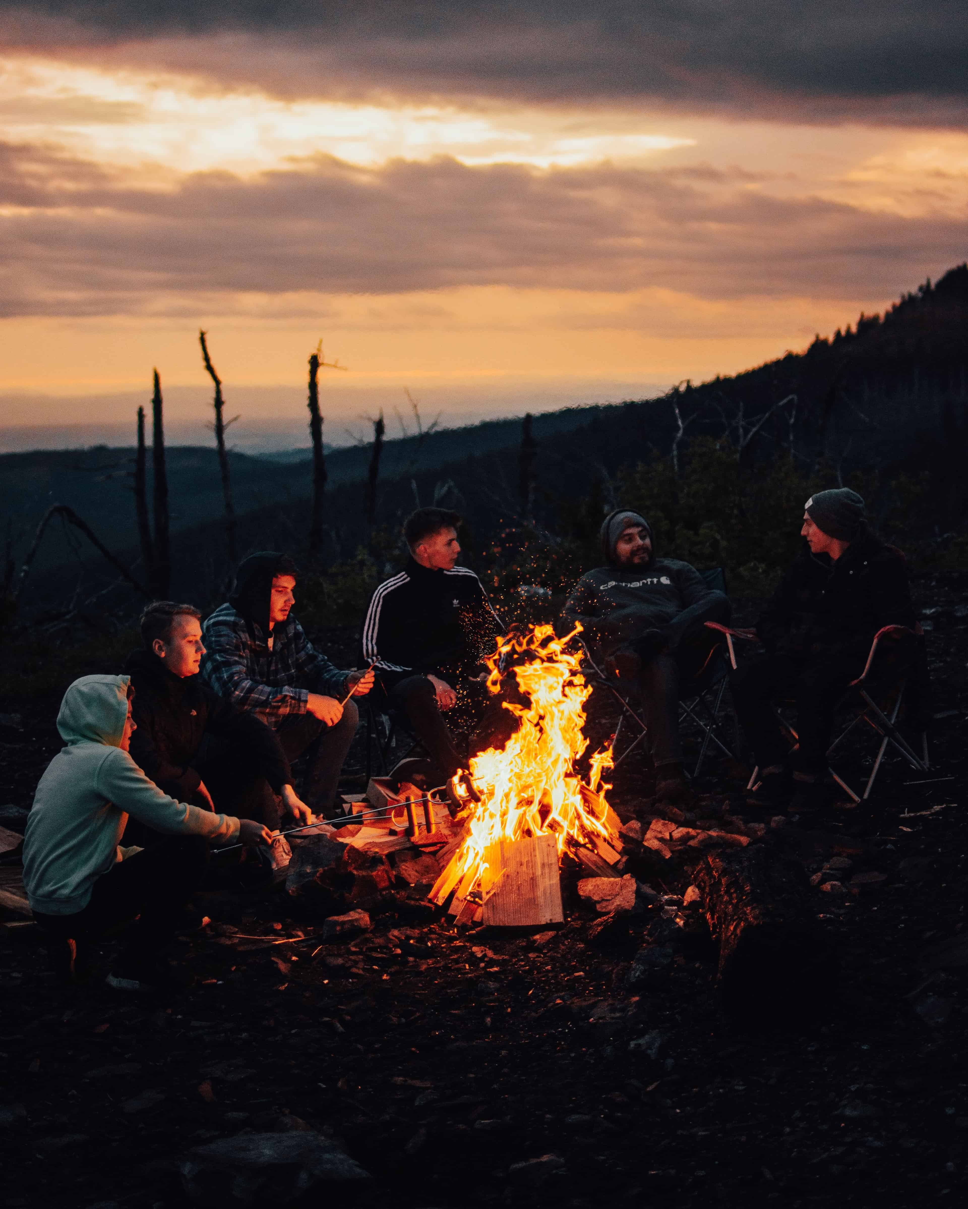 Friends gathered around a campfire at dusk